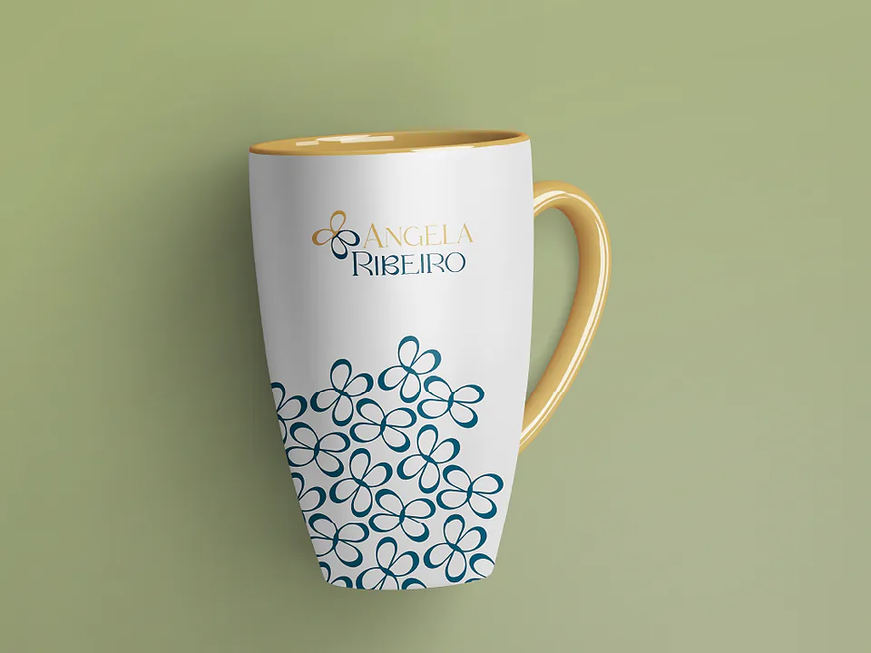 Caneca branca com padrão de pétalas azuis e interior dourado, sobre fundo verde oliva