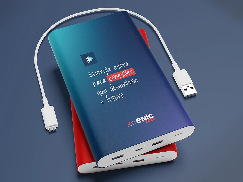 Dois carregadores portáteis, azul-marinho e vermelho, com cabo USB e a frase "Energia extra para conexões que desenham o futuro"