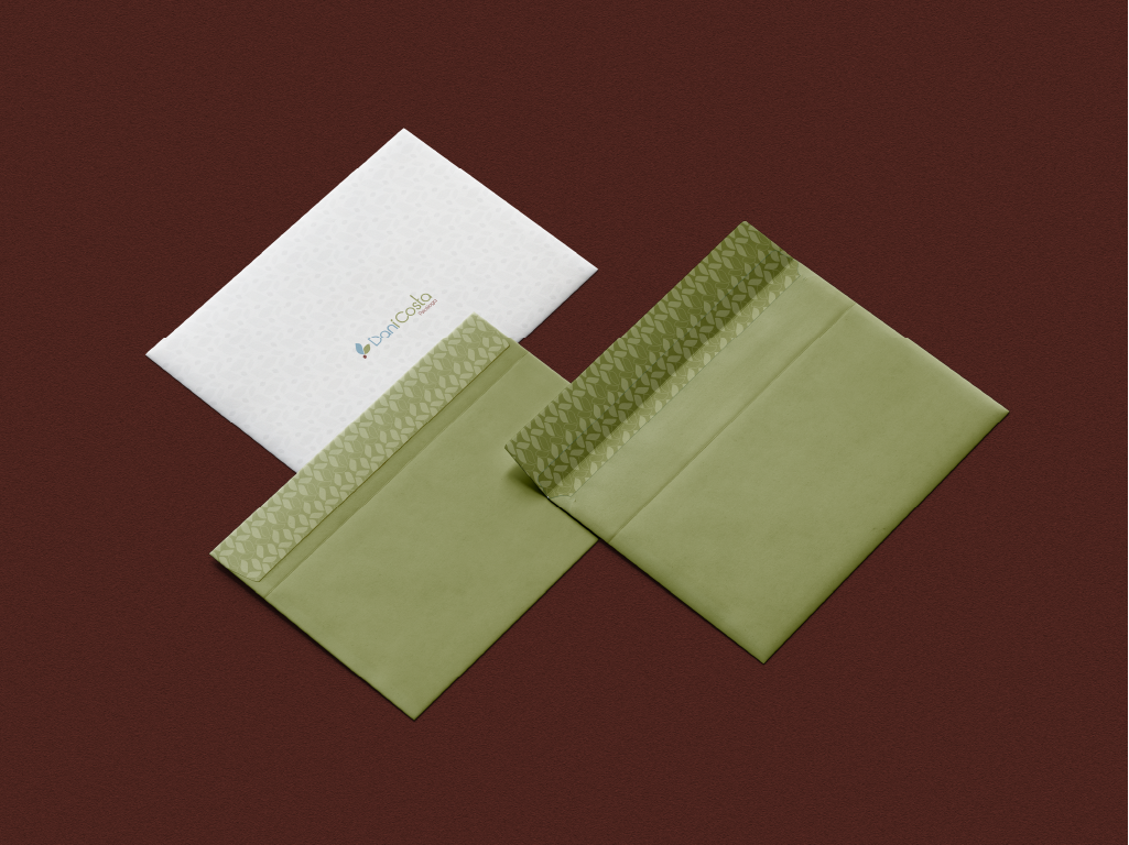 Envelopes verdes e branco com padrão de folhas aplicado, compondo a papelaria da marca Dani Costa Psicóloga.
